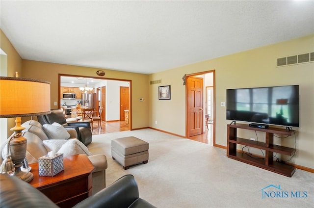living area featuring a chandelier, visible vents, light carpet, and baseboards