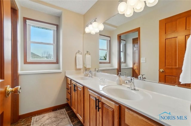 bathroom featuring an inviting chandelier, a sink, and plenty of natural light