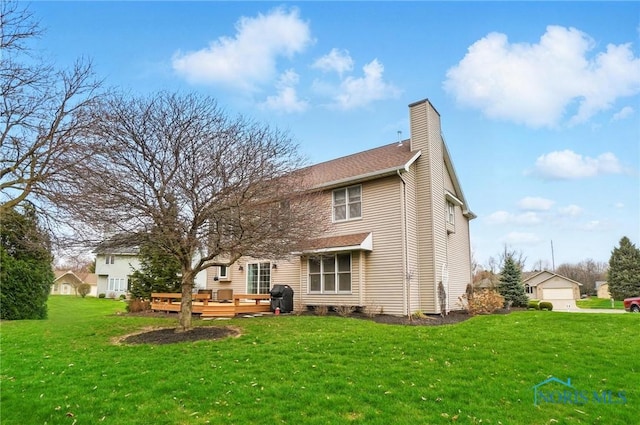 rear view of house featuring a deck, a lawn, and a chimney