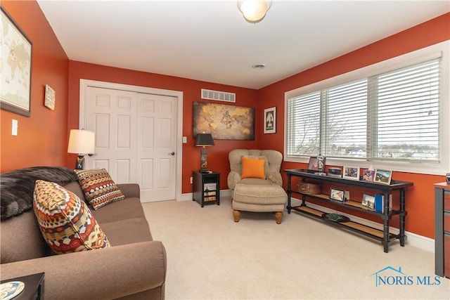 carpeted living area with baseboards and visible vents