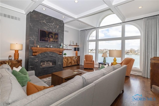 living area with dark wood-style flooring, a water view, a fireplace, coffered ceiling, and ornamental molding