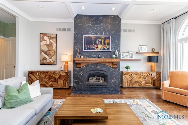 living area featuring wood finished floors, visible vents, a fireplace, and crown molding
