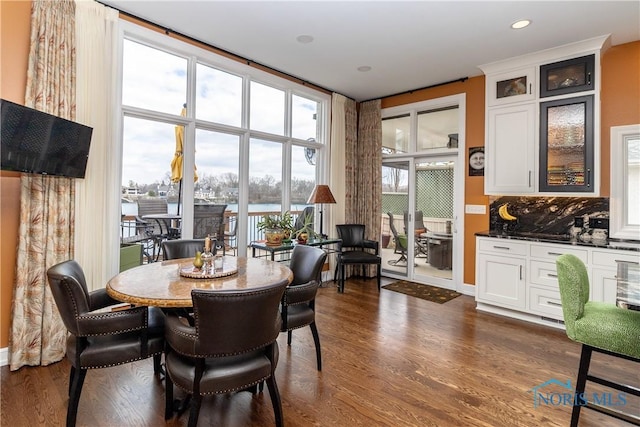 dining space featuring dark wood finished floors, expansive windows, a water view, and plenty of natural light