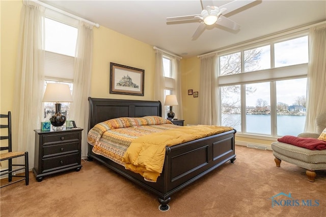 bedroom with visible vents, carpet, and a water view