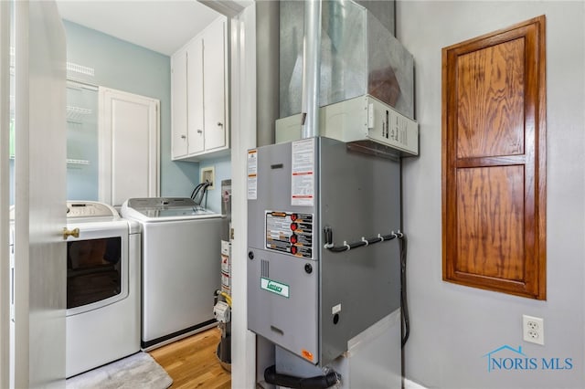 242 E Yates Ave, Findlay, OH 45840 - washroom featuring washer and dryer, cabinet space, heating unit, and light wood-style floors