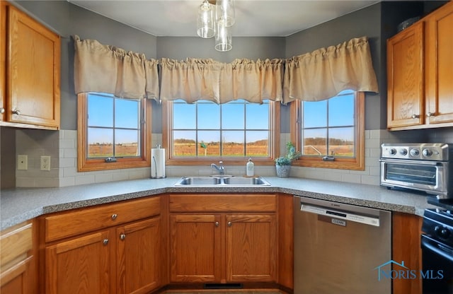 kitchen with brown cabinets, backsplash, stainless steel dishwasher, a sink, and gas stove