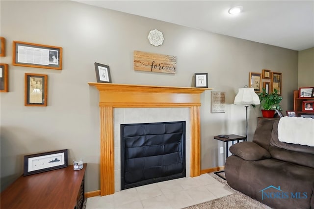 living room featuring a tiled fireplace and baseboards