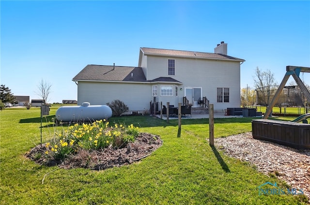 rear view of house with a patio area, a chimney, and a yard