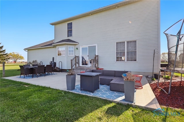 back of house featuring an outdoor living space, a patio area, a lawn, and a trampoline