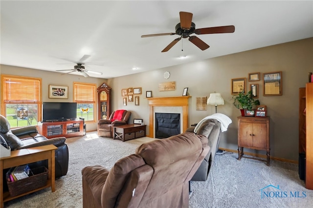 living area with a ceiling fan, a glass covered fireplace, and carpet