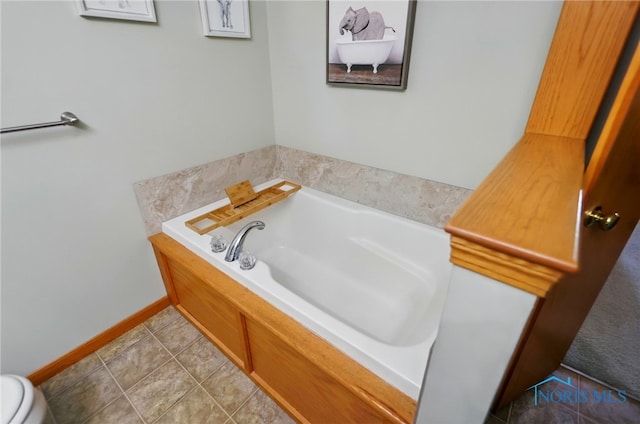 bathroom featuring a bath, toilet, tile patterned floors, and baseboards