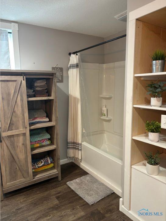 full bathroom with shower / tub combo with curtain and wood finished floors