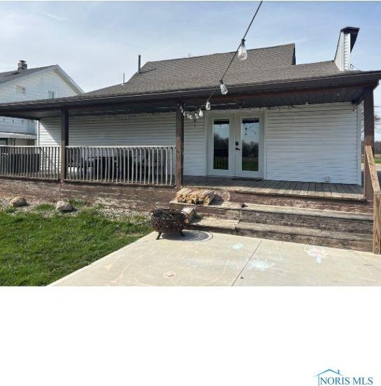 back of property with a patio, french doors, and a shingled roof