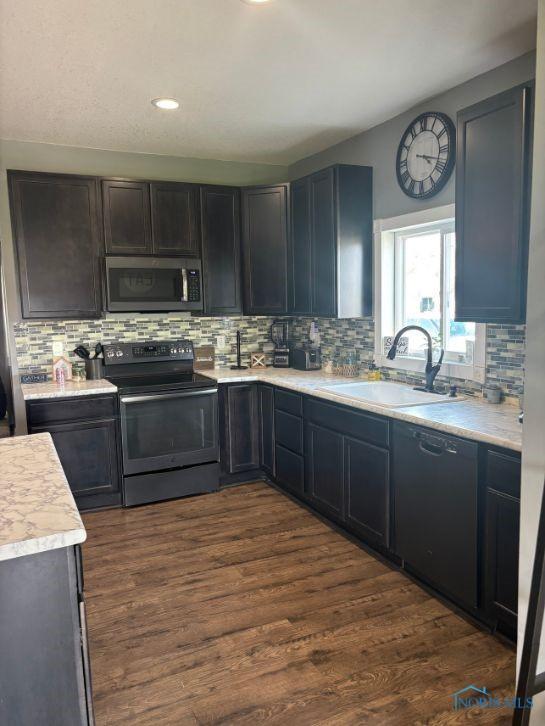 kitchen featuring light countertops, a sink, backsplash, and black appliances