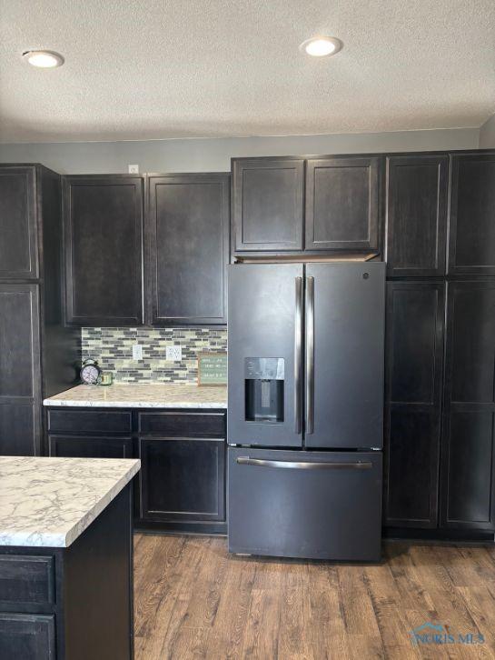 kitchen featuring stainless steel fridge with ice dispenser, tasteful backsplash, wood finished floors, and a textured ceiling