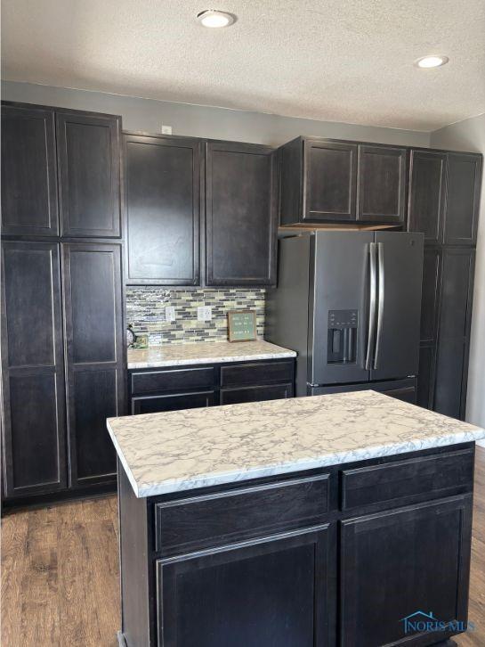 kitchen featuring stainless steel fridge with ice dispenser, tasteful backsplash, dark wood-style floors, and a textured ceiling