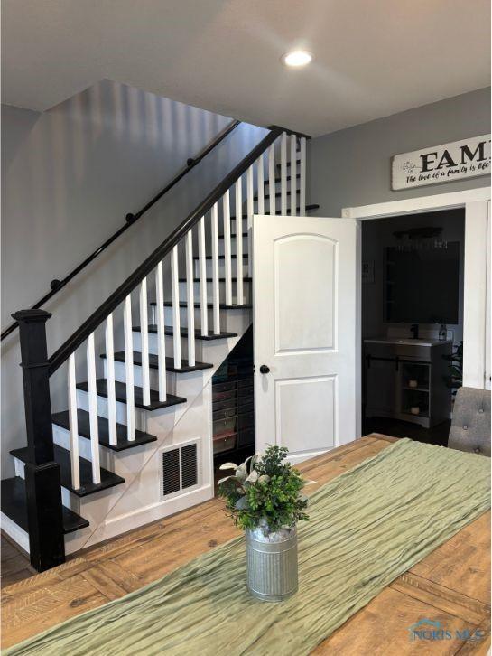 staircase featuring wood finished floors, visible vents, and recessed lighting