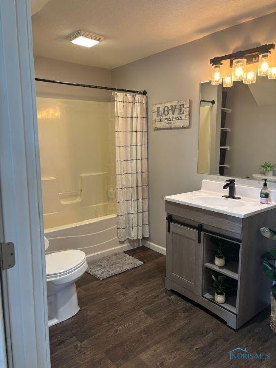 full bath with shower / tub combo with curtain, vanity, toilet, and wood finished floors