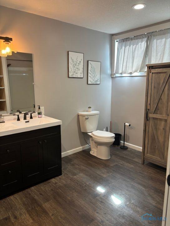 bathroom featuring toilet, wood finished floors, vanity, and baseboards