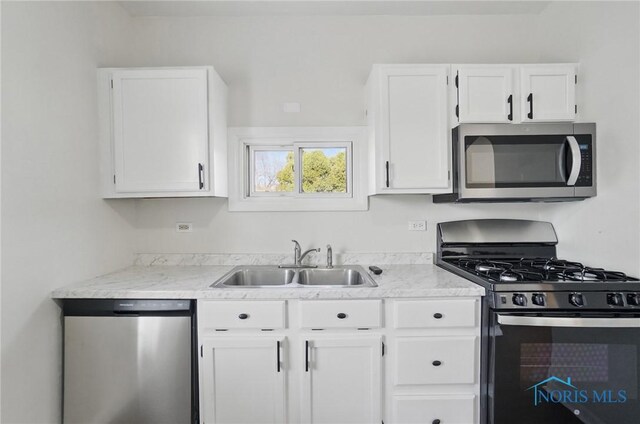 kitchen featuring white cabinets, light countertops, appliances with stainless steel finishes, and a sink