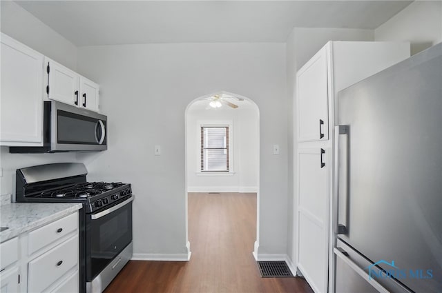 kitchen featuring white cabinets, stainless steel appliances, a ceiling fan, baseboards, and dark wood-style flooring