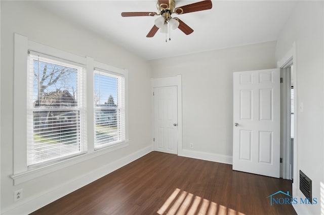 unfurnished bedroom with dark wood finished floors, baseboards, a ceiling fan, and visible vents