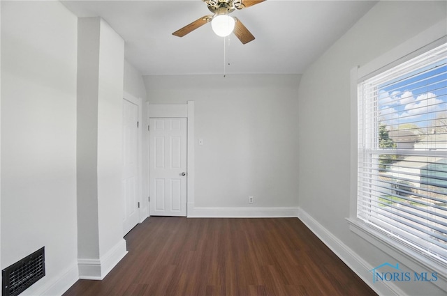 spare room featuring baseboards, wood finished floors, visible vents, and ceiling fan