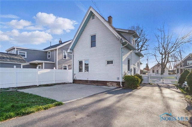 view of side of property featuring a chimney, fence, and a patio