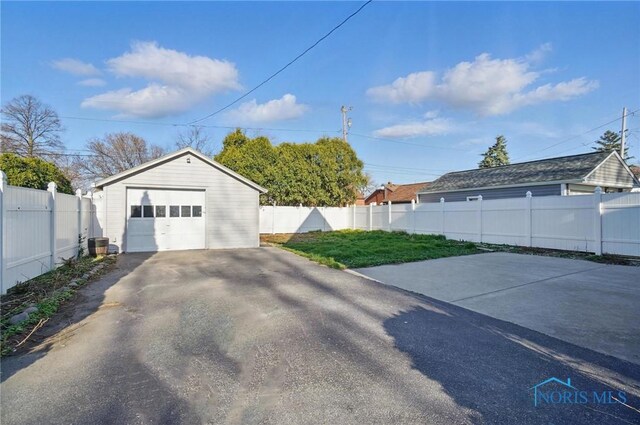 detached garage featuring driveway and fence