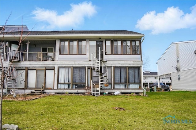 rear view of property with a sunroom, entry steps, a yard, and stairway