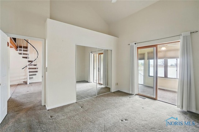 unfurnished room with baseboards, carpet floors, stairs, visible vents, and high vaulted ceiling