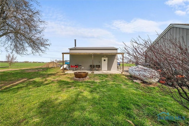 back of property with a fire pit, a yard, and a patio