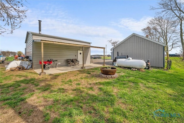 back of house featuring a patio area, a lawn, and an outdoor fire pit