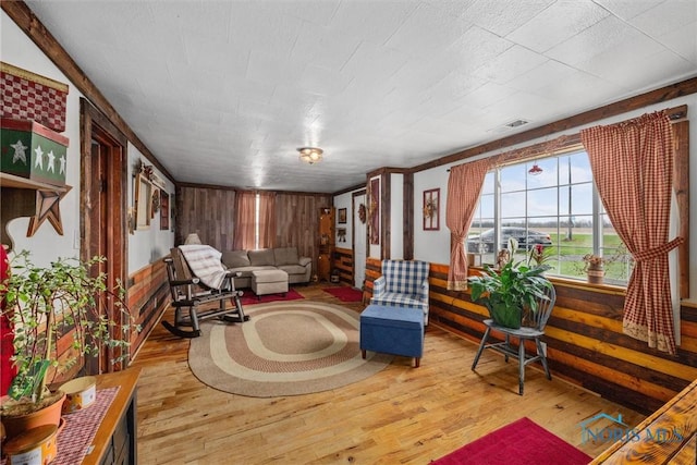 sitting room featuring wood finished floors, visible vents, and wood walls