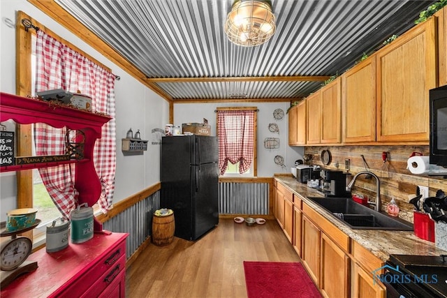 kitchen with black appliances, a wealth of natural light, a sink, and light wood-style floors