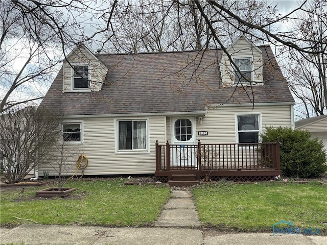 cape cod house with a front lawn, roof with shingles, and a deck