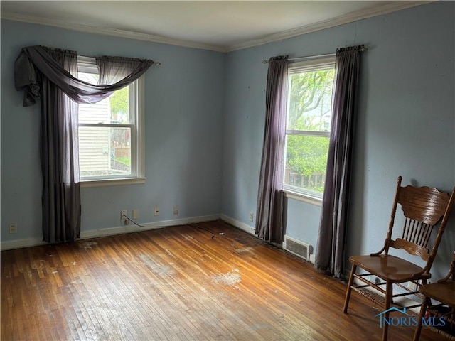spare room with crown molding, plenty of natural light, hardwood / wood-style floors, and visible vents