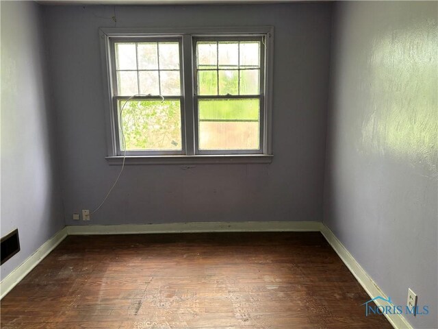 empty room with baseboards, visible vents, and dark wood-style floors