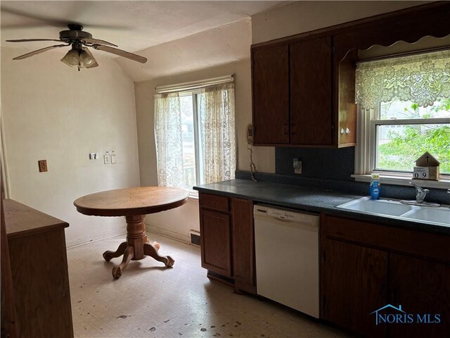 kitchen with dark countertops, a sink, dishwasher, a ceiling fan, and light floors