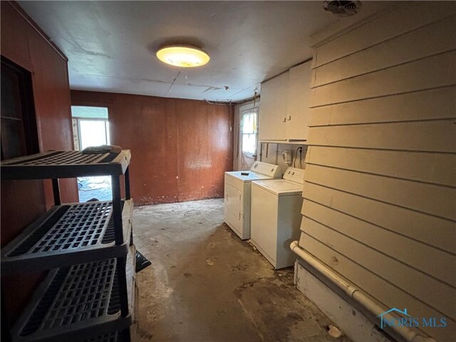 laundry area with laundry area, wood walls, and washing machine and clothes dryer