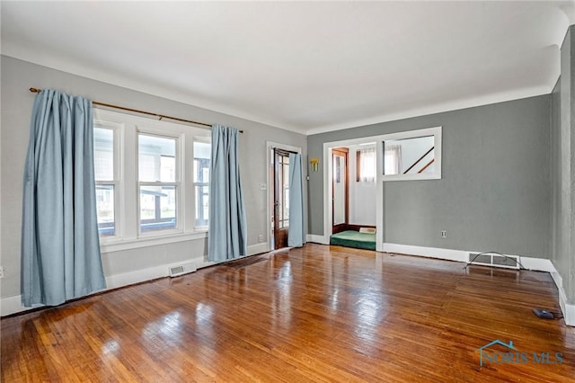 unfurnished room featuring visible vents, baseboards, and wood finished floors