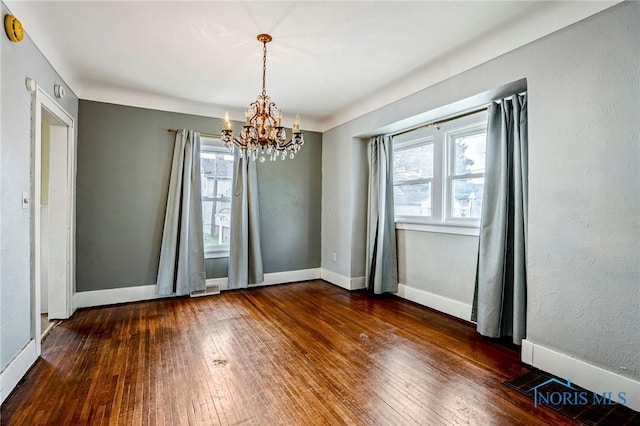 unfurnished dining area with hardwood / wood-style floors, an inviting chandelier, baseboards, and visible vents