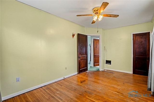 spare room with ceiling fan, wood finished floors, and baseboards