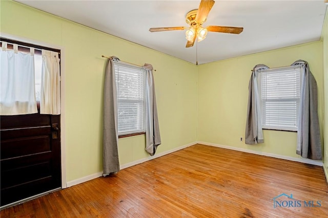 unfurnished room featuring a healthy amount of sunlight, baseboards, and hardwood / wood-style flooring