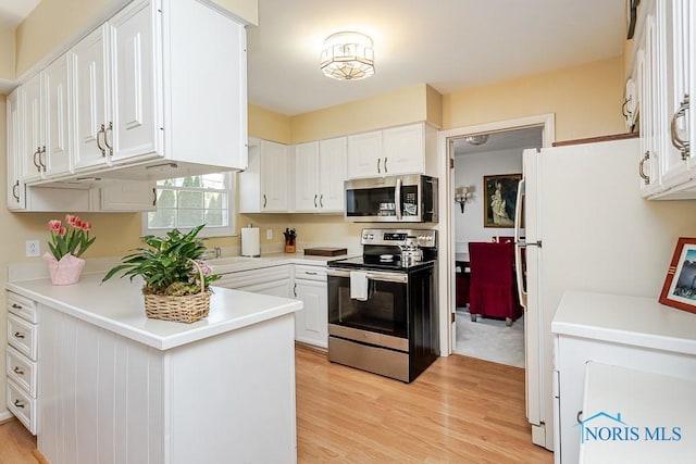 kitchen with white cabinets, stainless steel appliances, light countertops, and light wood finished floors
