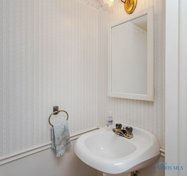 bathroom with wallpapered walls and a sink