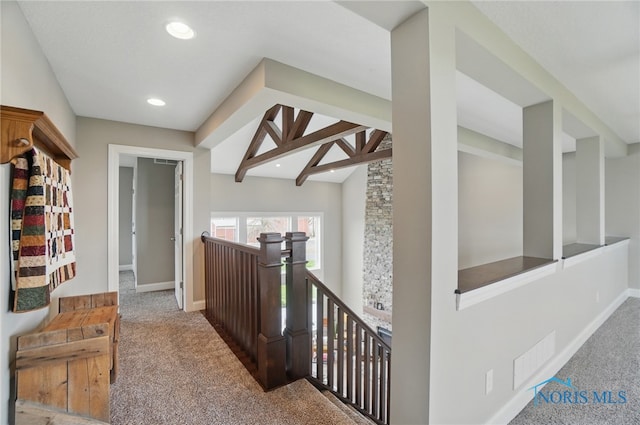hall with carpet floors, an upstairs landing, visible vents, and baseboards