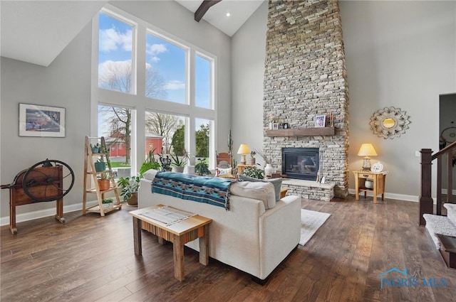 living area with baseboards, hardwood / wood-style floors, a fireplace, and high vaulted ceiling
