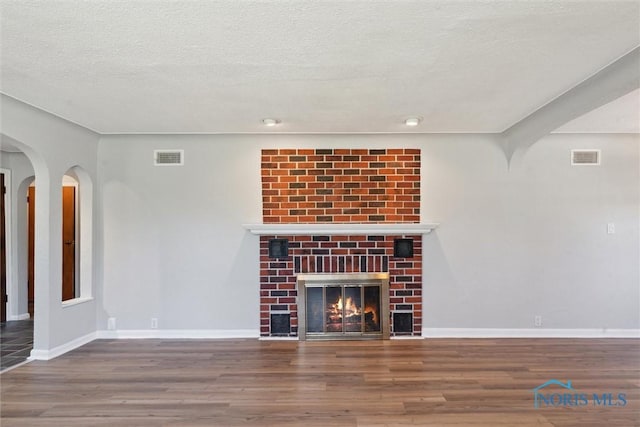 3105 W Laskey Rd, Toledo, OH 43613 - unfurnished living room featuring wood finished floors, visible vents, baseboards, a fireplace, and a textured ceiling