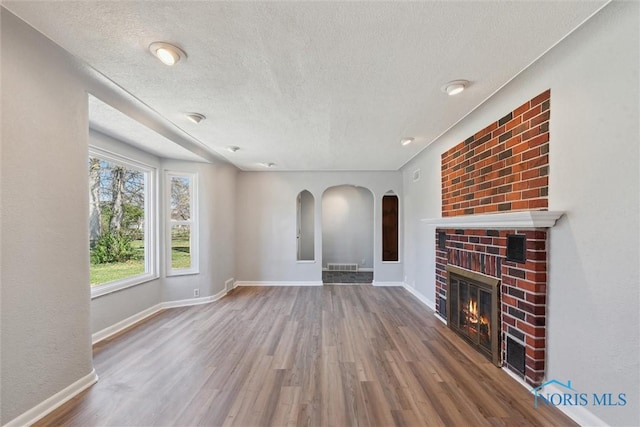 3105 W Laskey Rd, Toledo, OH 43613 - unfurnished living room with wood finished floors, a textured ceiling, visible vents, and a fireplace